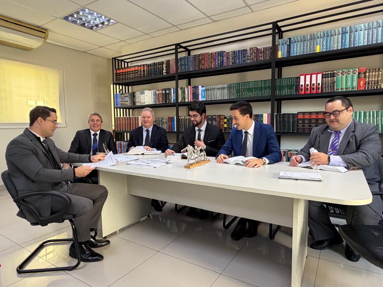 Equipe do Emerson Longhi Advogados reunida em sala com biblioteca jurídica.
